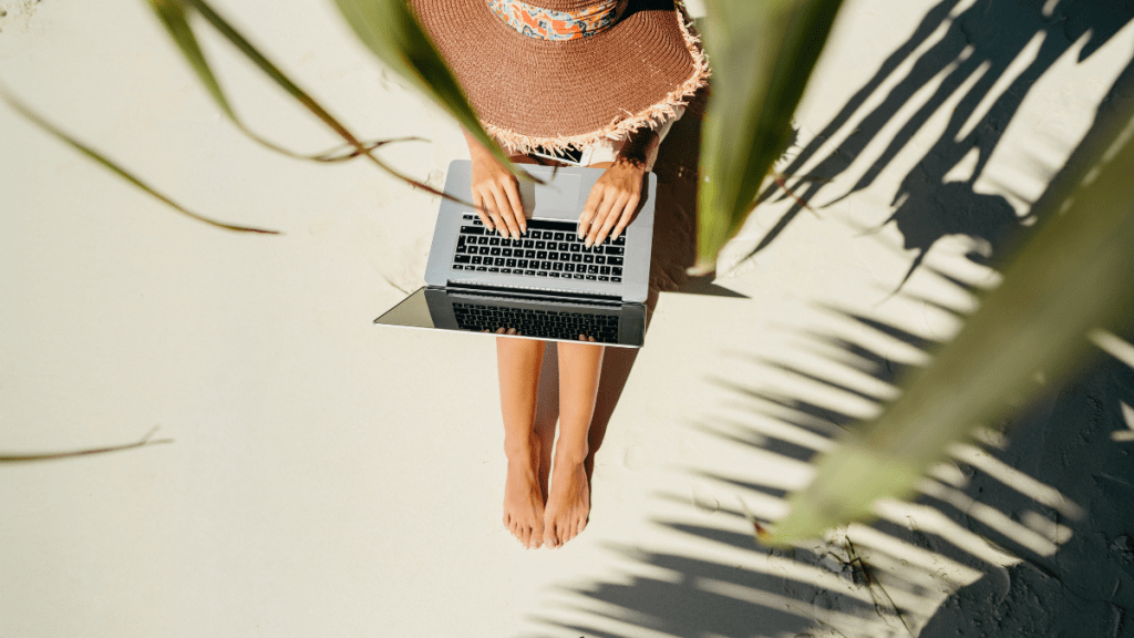 A woman working on her laptop on a beach