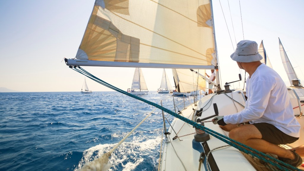 hombre al timón de un yate de vela